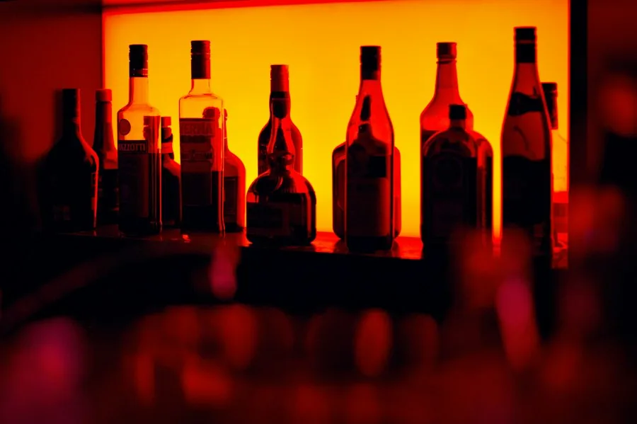 Bottles backlit on a bar shelf